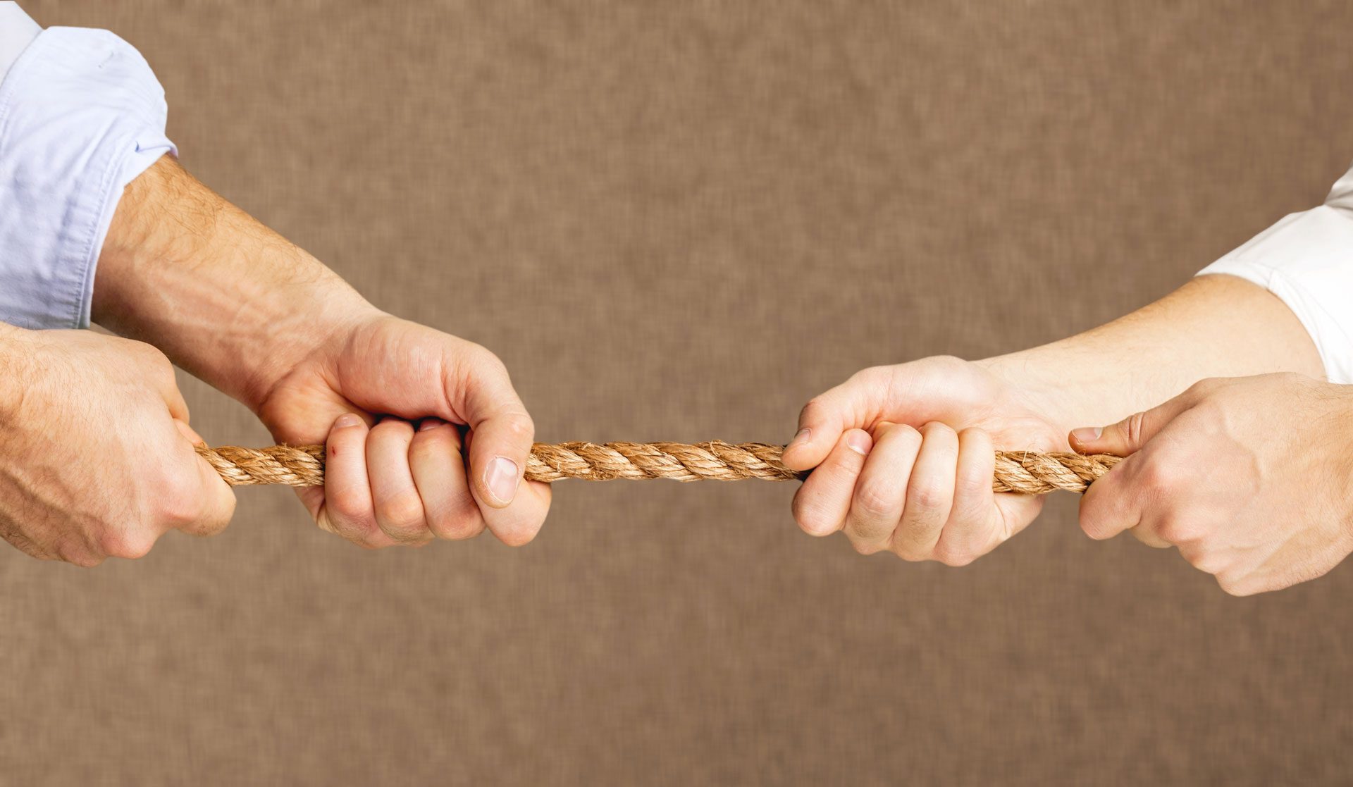 Zwei Personen ziehen mit ihren Händen an einem Seil.