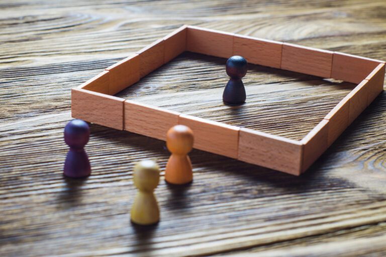 Eine Gruppe kleiner Holzspielfiguren, die auf einem Holztisch sitzen.