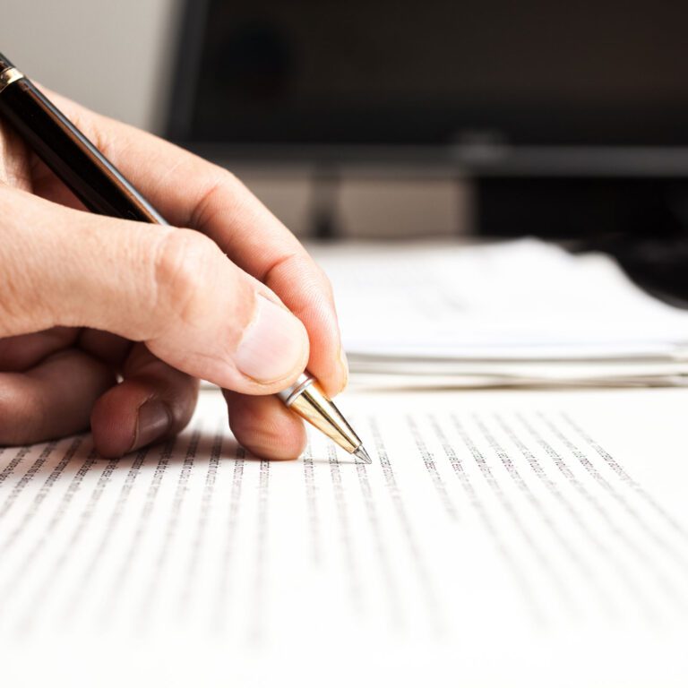 Eine Person schreibt mit einem Stift auf ein Script Dokument.